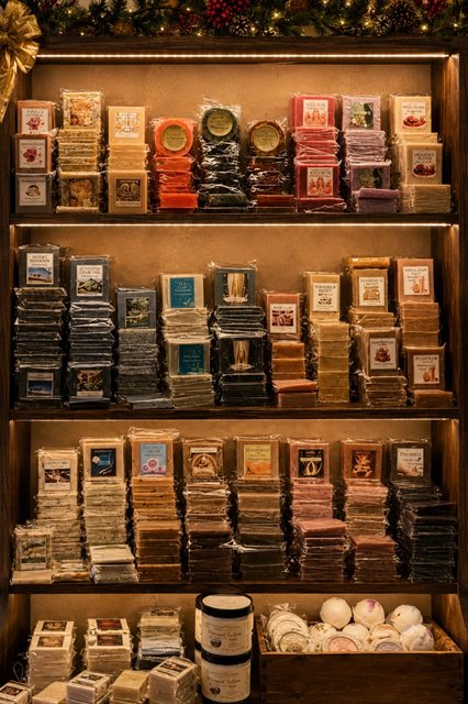 A lit wooden shelf filled with stacks of handmade soap bars in many colors