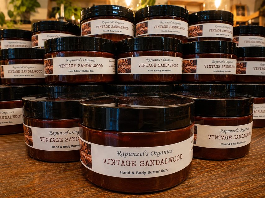 Jars of Vintage Sandalwood hand and body butter stacked on a wooden table